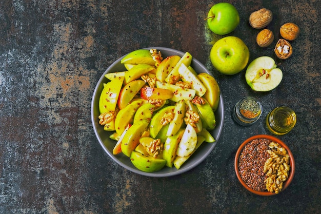 Vegan appel salade in een kom. Gezonde salade met appels, walnoten, kruiden en lijnzaad.