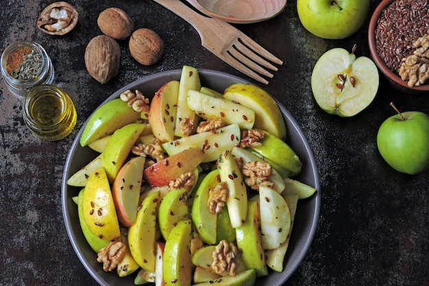 Vegan appel salade in een kom. Gezonde salade met appels, walnoten, kruiden en lijnzaad.