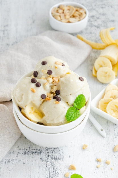 Vegan banana ice cream in a bowl with peanuts and chocolate\
healthy dessert vertical copy space