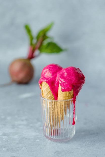 Gelato vegano alla barbabietola in un cono di cialda in un bicchiere su sfondo grigio. dessert vegano sano