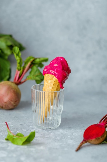 Vegan beetroot ice cream in a waffle cone in a glass on a gray background. Healthy vegan dessert