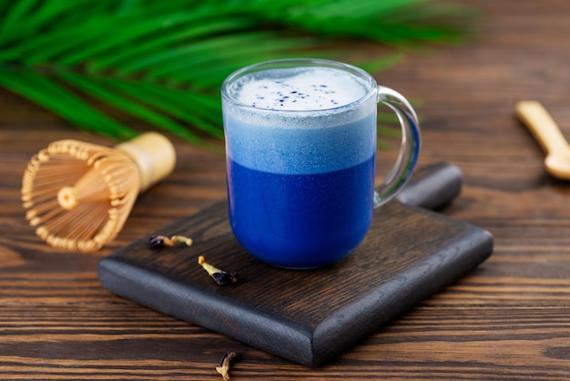 Vegan blue matcha latte drink or Anchan tea from clitoria flowers with coconut milk palm branch