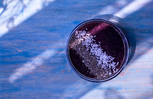 Colazione vegana frullato di mirtilli con semi di chia cocco su sfondo di legno viola spazio di copia