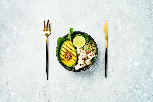 Vegan boeddha bowl avocado tofu kaas vlas pompoenpitten en spinazie het concept van gezond eten op een stenen achtergrond bovenaanzicht