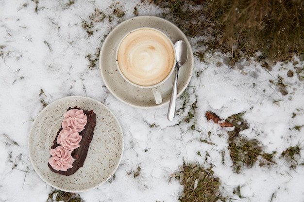 Vegan brownie cake dessert with cup of cappuccino outdoor at the snowy day Coffee with dessert