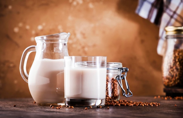 Vegan Buckwheat plant based milk in bottles closeup brown background Non dairy alternative milk Healthy vegetarian food and drink concept Copy space