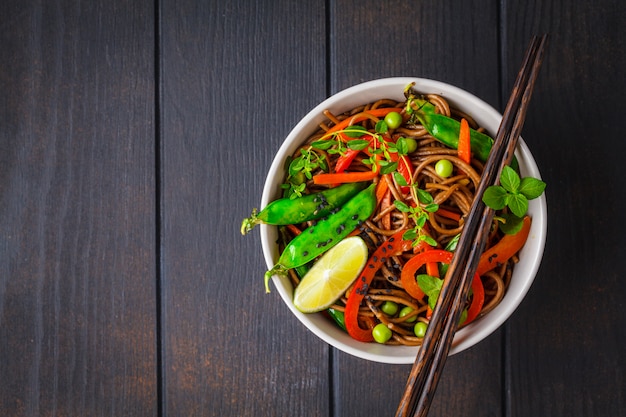 Tagliatelle di soba di grano saraceno vegano con verdure, vista dall'alto.