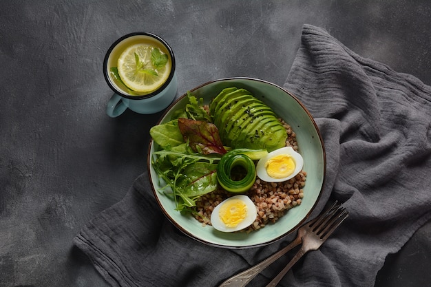 Vegan buddha bowl with buckwheat, avocado, boiled eggs, cucumber, arugula beet leaves. diet, detox, healthy food concept