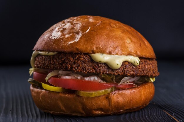 Vegan burger Falafel en ambachtelijk broodje op een stenen dienblad Burger Veganer Broodje of sla falafel sla tomaat ingelegde komkommer