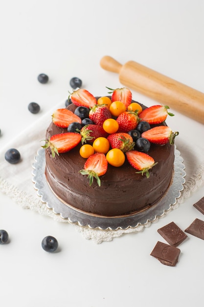 Foto torta al cioccolato vegana con cacao, fragole e uva spina dorata in diverse angolazioni