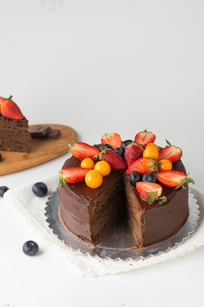 Foto torta al cioccolato vegana con cacao, fragole e uva spina dorata in diverse angolazioni