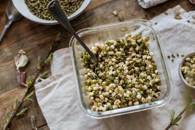 Веганская кухня. проросшие азиатские бобы в стеклянной банке на деревянном столе.