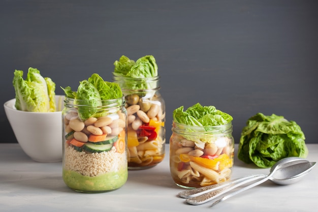 Vegan couscous en pastasalade in glazen potten met groenten bonen