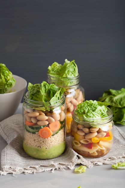 Vegan couscous en pastasalade in glazen potten met groenten bonen