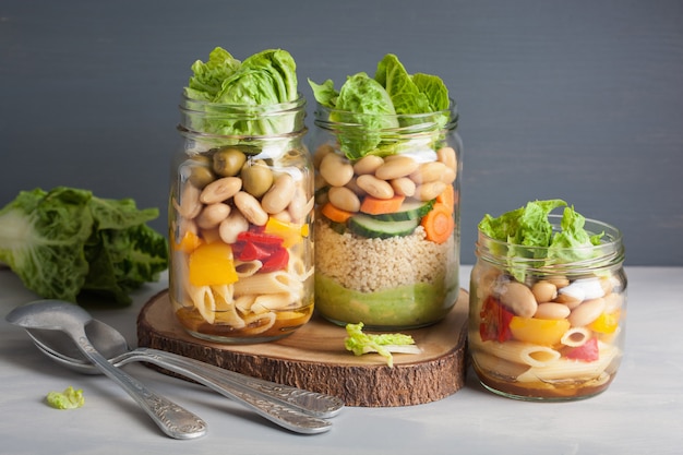 Vegan couscous en pastasalade in glazen potten met groenten bonen