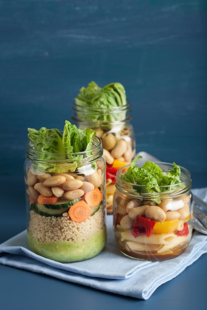 Vegan couscous and pasta salad in mason jars with vegetables beans