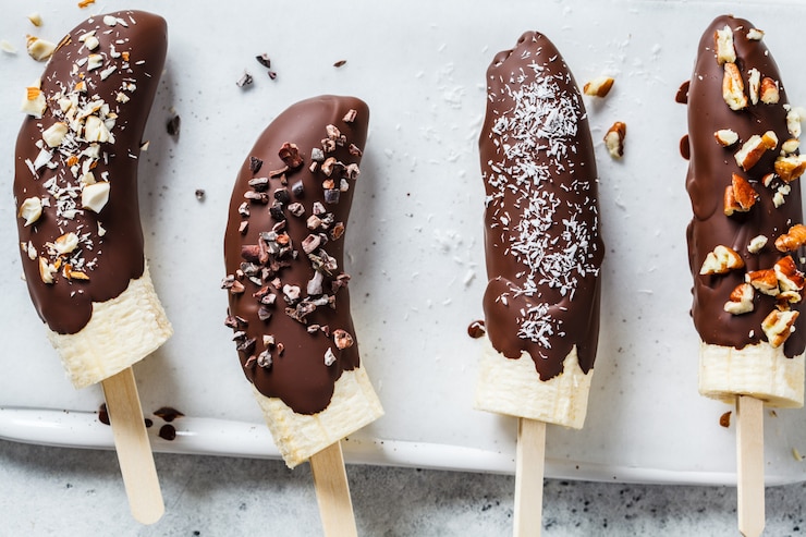 Vegan dessert for kids. Banana in dark chocolate with nuts.