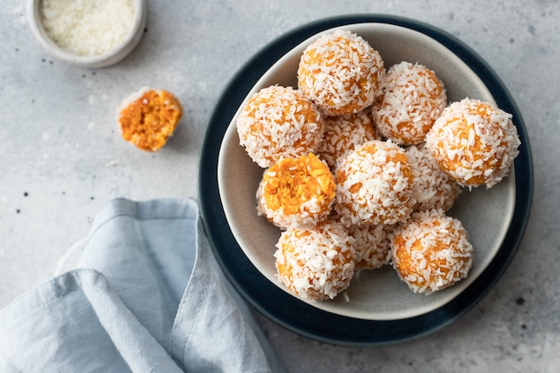 Vegan energy bliss balls with dried apricots and coconut in blue bowl raw vegan dessert