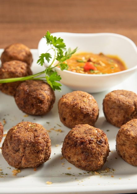 Vegan food chickpea meatball and sauce on a white plate over wood selective focus