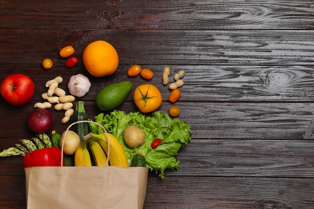 Vegan food delivery Bag met verschillende verse groenten noten en fruit op houten tafel plat leg ruimte voor tekst