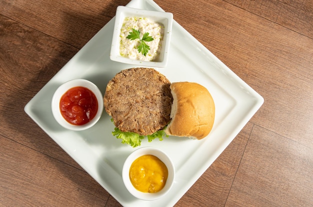 Vegan food Vegan burger and sauces on a white plate over wood top view