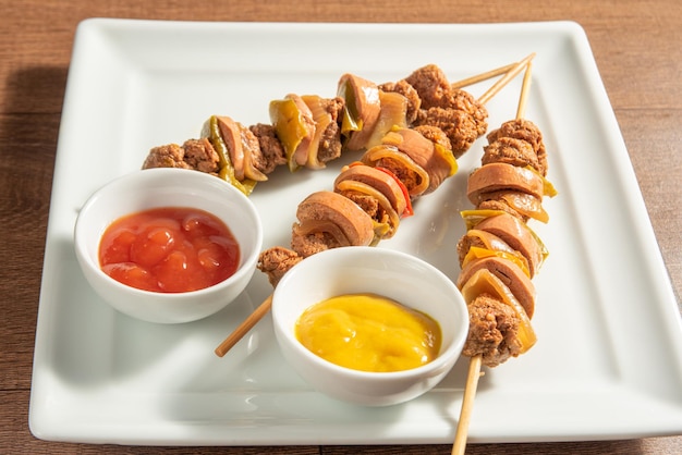 Vegan food vegan skewers and sauces on a white plate over wood
selective focus