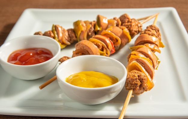 Vegan food vegan skewers and sauces on a white plate over wood
selective focus