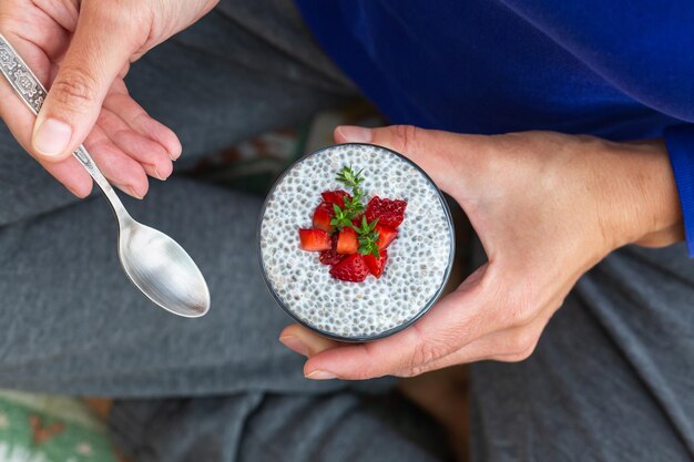 Foto mangiare sano e seguire una dieta vegana concetto di cibo mani femminili che tengono il budino di chia con fragole