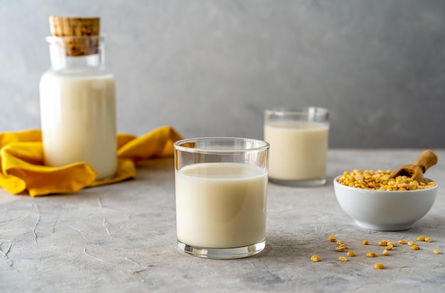 Vegan healthy pea milk in glass bottle and two glasses concrete background pea grains. Copy space