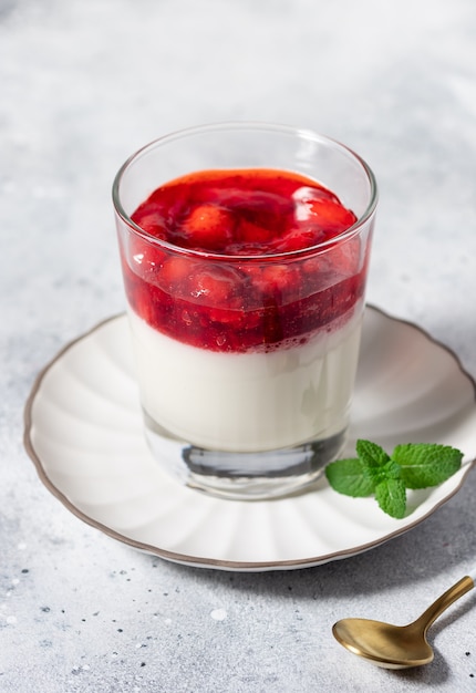 Vegan kokos panna cotta met aardbeien in glas op grijze achtergrond