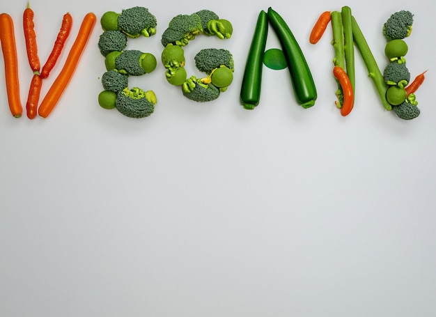 Photo vegan lettering made out of vegetable on white background