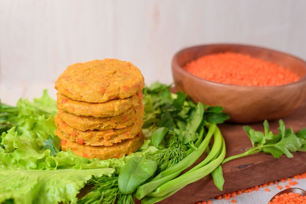 Vegan linzen en wortel hamburgers in een houten plaat met groene salade op een licht