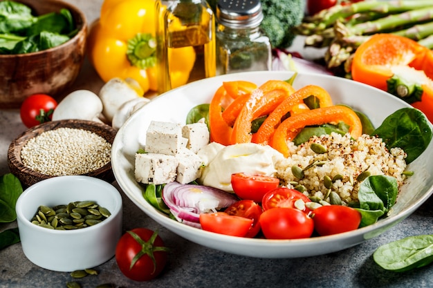 Photo vegan lunch bowl with quinoa, broccoli, hummus and mushrooms.