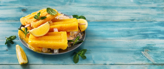 Vegan mango sorbet popsicles on trendy turquoise background