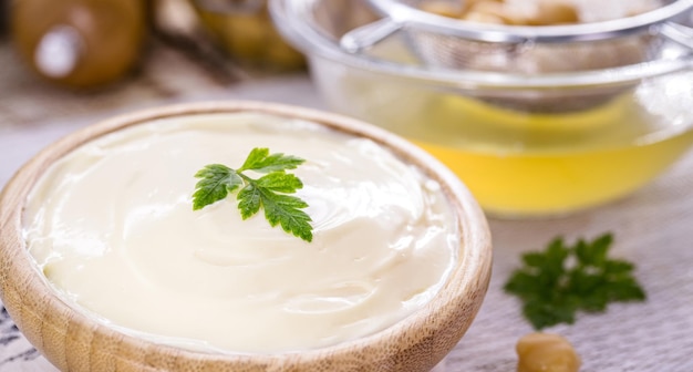 Vegan mayonaise gemaakt van kikkererwten en legemus met een potje aquafaba op de achtergrond ei of melkvrij ingrediënt