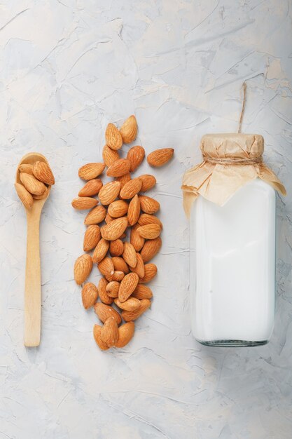 Vegan Milk from a handful of organic almond seeds in a bottle on a light background.