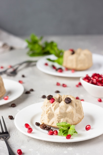 Vegan mini cheesecakes with coffee and banana garnished with coffee beans, pomegranate and mint