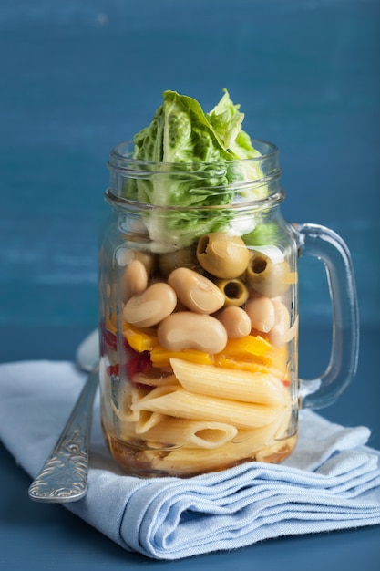 Vegan pasta salad in mason jar with vegetables beans olives