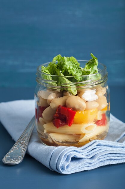 Vegan pasta salad in mason jar with vegetables beans