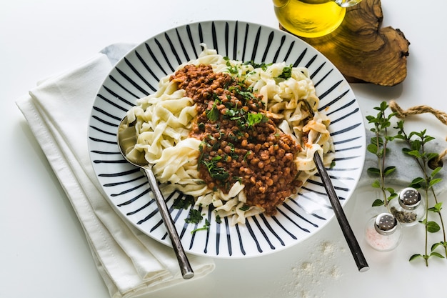 Vegan pasta with lentil and tomato sauce in a plate on the table