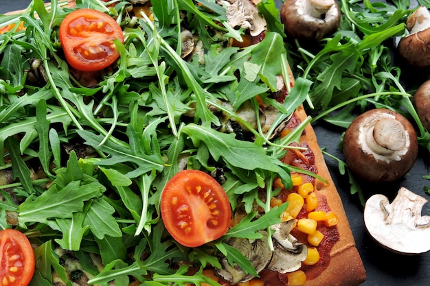 Vegan pizza with mushrooms and fresh arugula. Square pizza with vegetables, mushrooms and arugula.