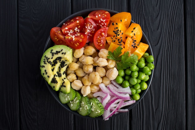 Vegan poke bowl with chickpea and vegetables in the dark bowl