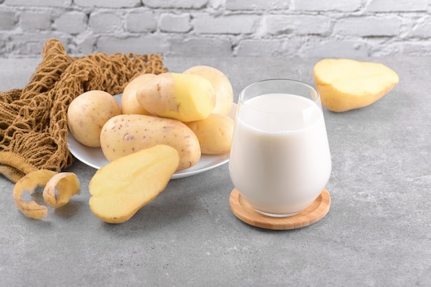 Vegan potato milk and potato on grey stone table background Plant based alternative milk replacer and lactose free