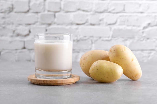 Vegan potato milk and potato on grey stone table background plant based alternative milk replacer