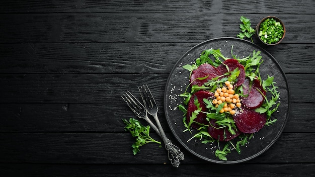 写真 ビーガンサラダビートルッコラとひよこ豆を黒い石のプレートに健康的なダイエット食品トップビューテキスト用の空きスペース