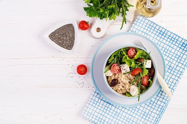 Vegan salad Breakfast bowl with oatmeal tomatoes cheese lettuce and olives Healthy food Vegetarian buddha bowl Top view