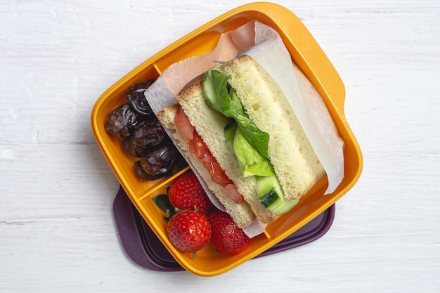 Vegan Sandwich in plastic container op houten achtergrond. Gezond voedselconcept