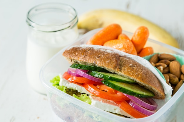 Vegan sandwich in lunch box with carrots and nuts