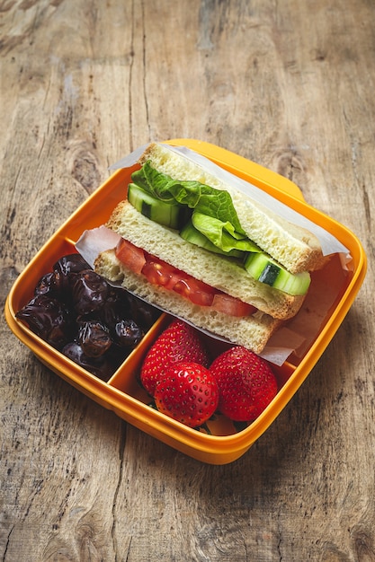 Vegan Sandwich in plastic container on wooden background