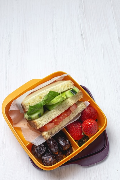 Vegan Sandwich in plastic container on wooden table. Healthy food concept